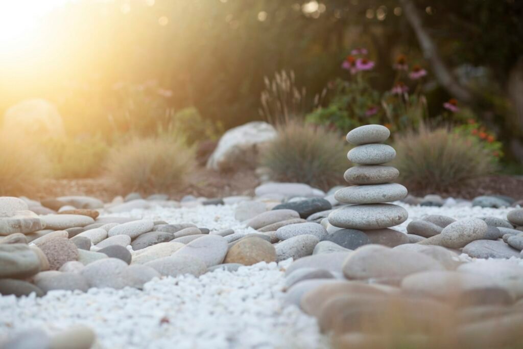 Piedras apiladas en equilibrio en un jardín con luz cálida
